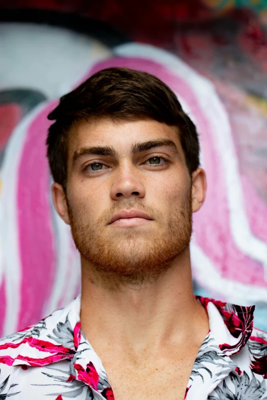 a man in a hawaiian shirt standing in front of a painting