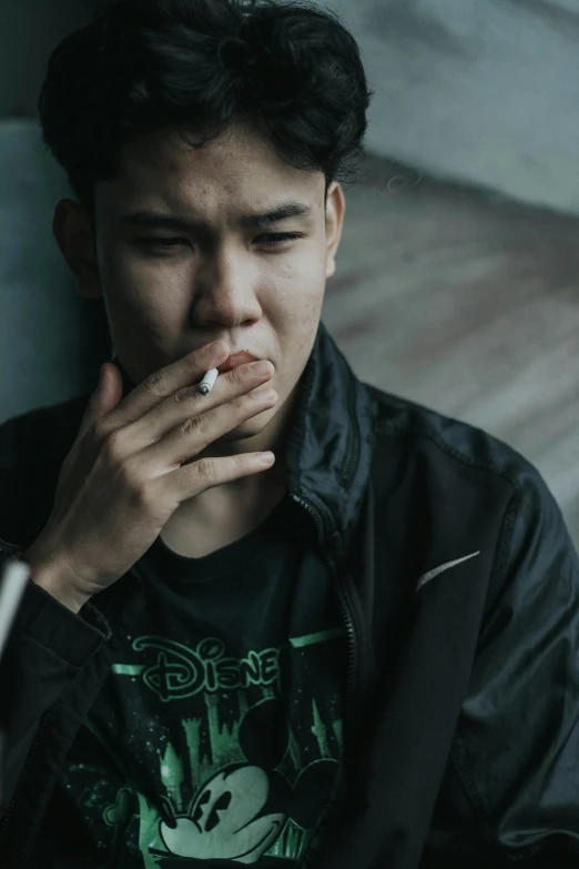 man smoking a cigarette while wearing a black jacket