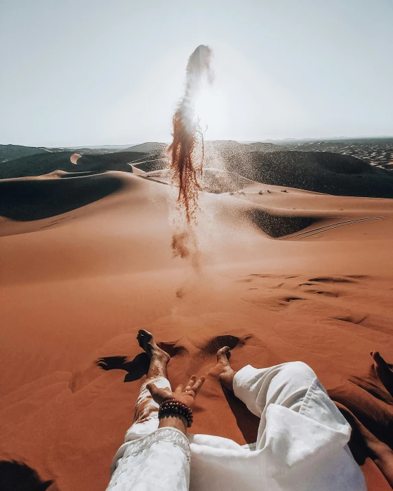 a person in white laying on the ground next to sand dunes