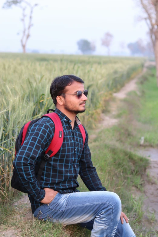 a man sits in the grass beside a path