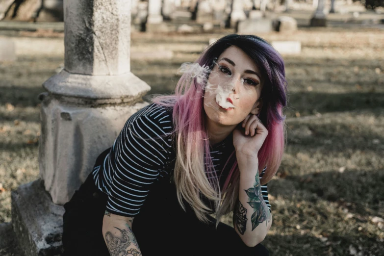 a woman with purple hair and piercings sitting in the grass