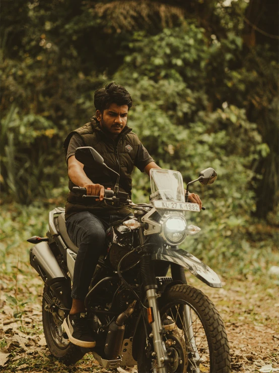 a man sitting on his motor bike in the woods