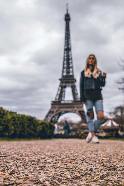 a girl is standing near the eiffel tower in paris