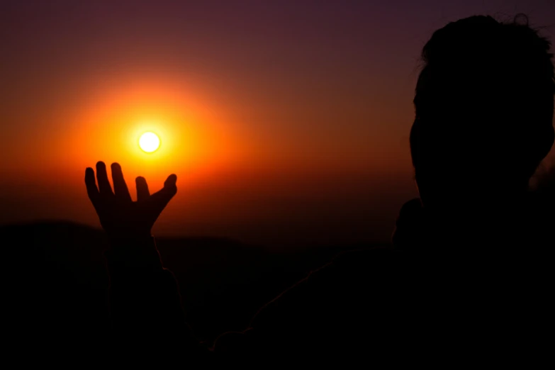 a person holds their hand up to the sun