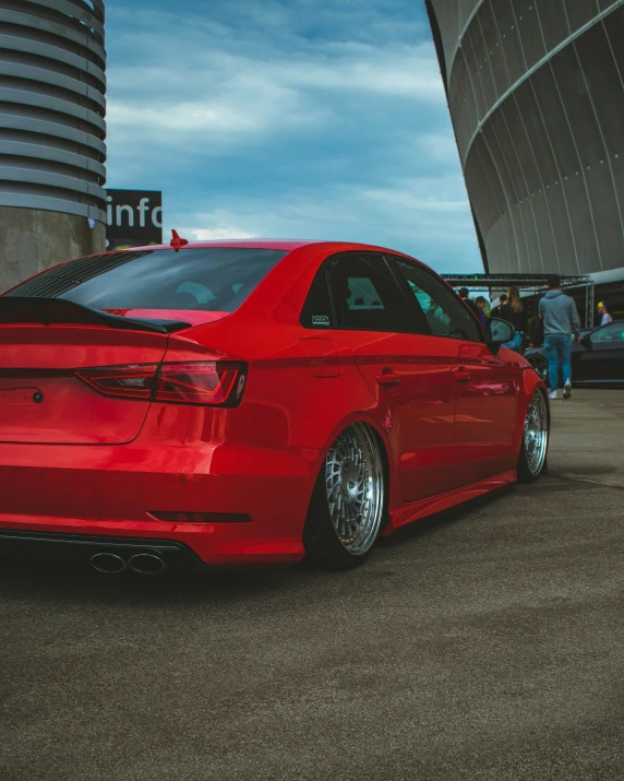 red sedan parked in front of a tall building