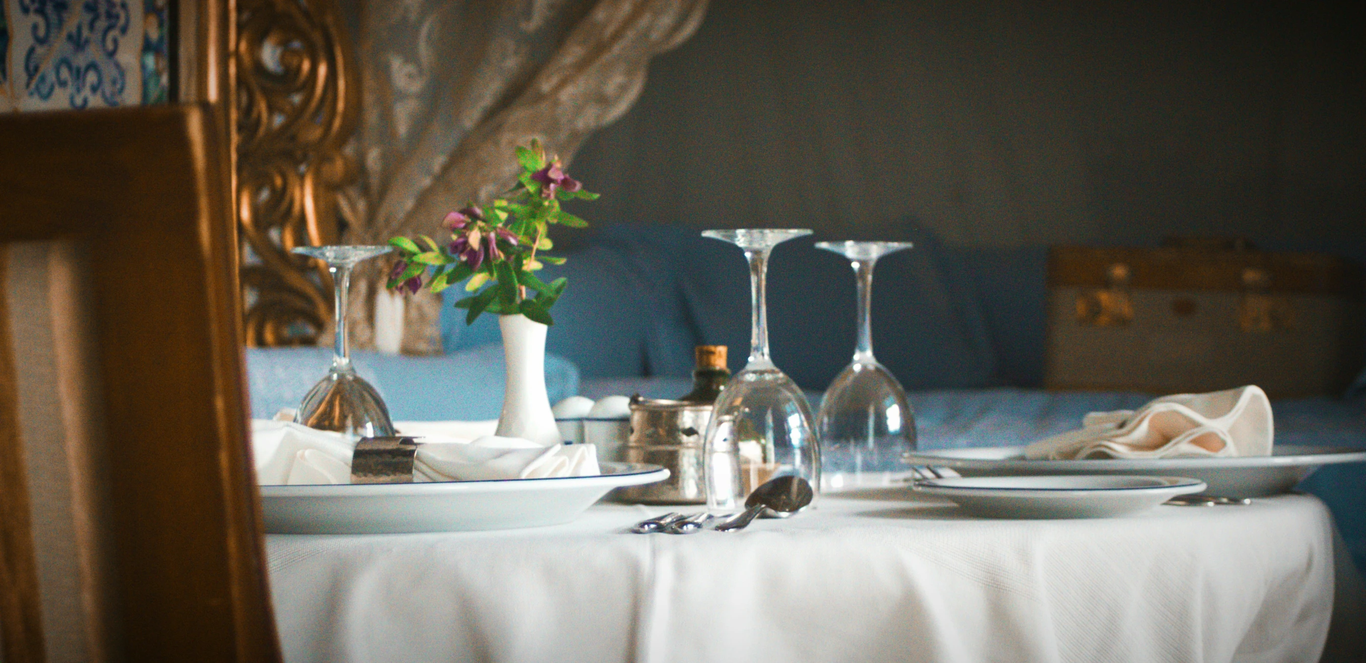 a table with plates, wine glasses and a vase