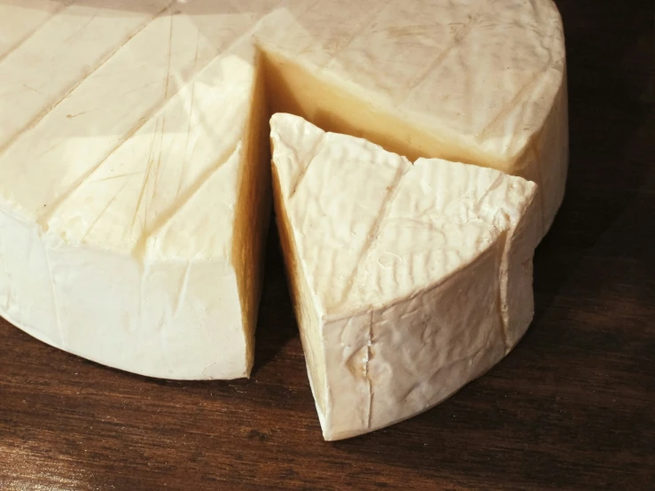 a wedge of cheese sitting on a wooden table