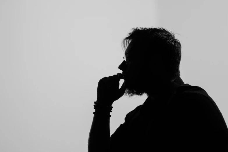 a silhouette of a man who is holding his nose in one hand