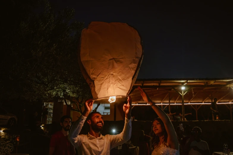 two people holding paper lanterns in the air