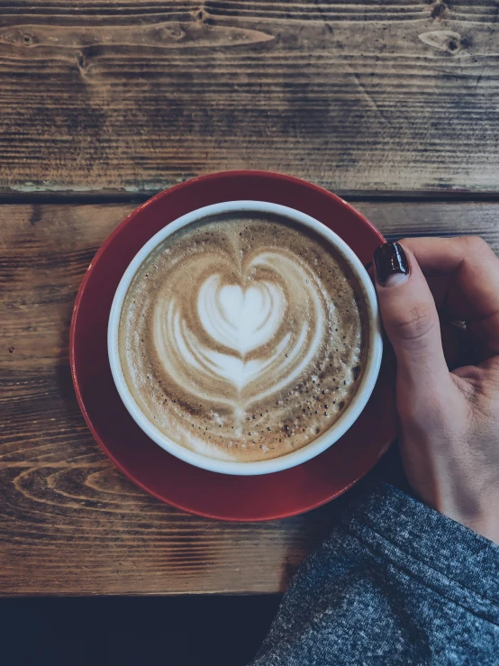 the heart on a latte in a red cup