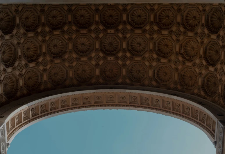 two birds fly around an arch which has intricate carving