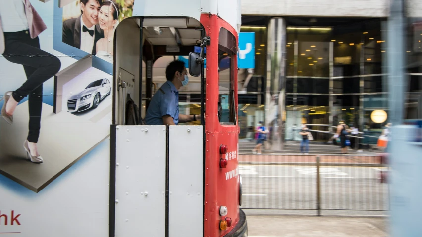 a city bus driving past a man in a blue shirt