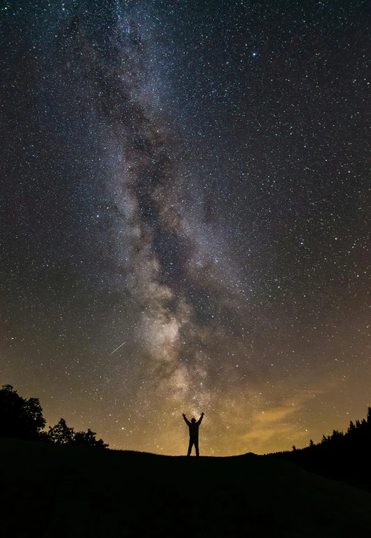 there is a person with their hands up in the air under the stars