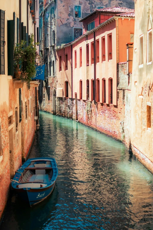 a blue boat in a body of water near buildings