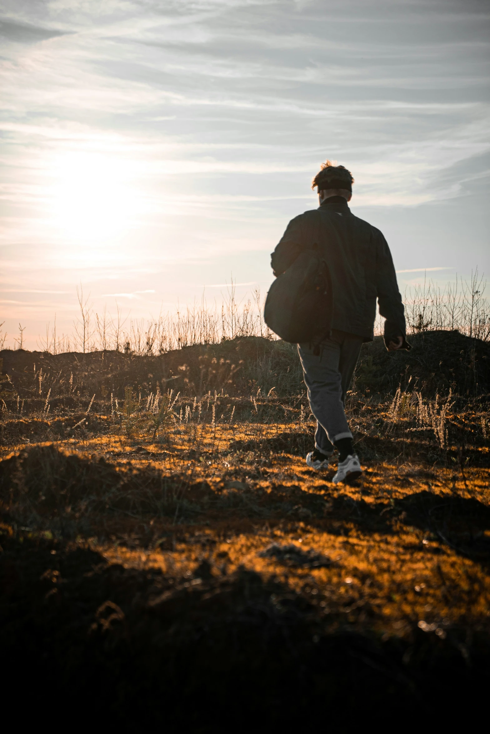 a man walking in the dirt towards the sun