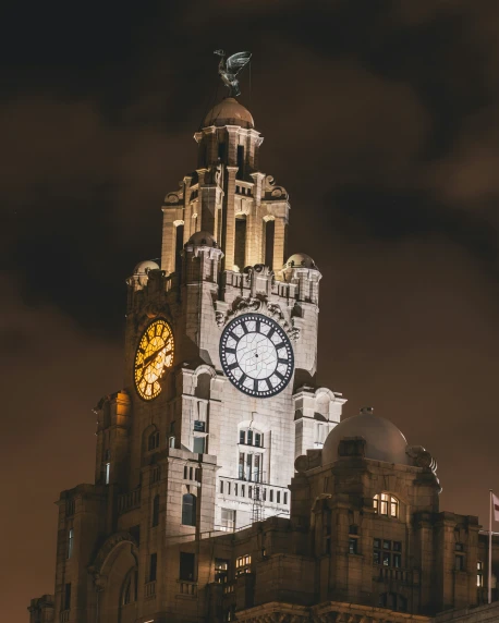 a clock tower lit up at night with cloudy skies