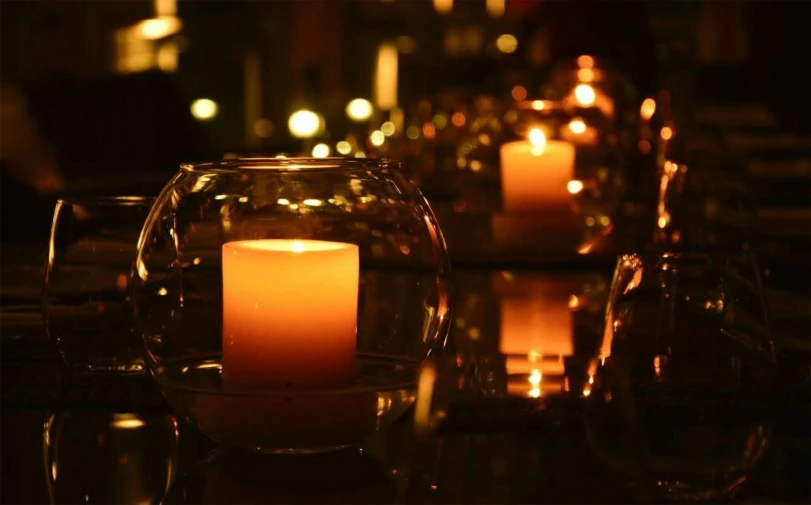 several lit candles sit in an empty glass vase