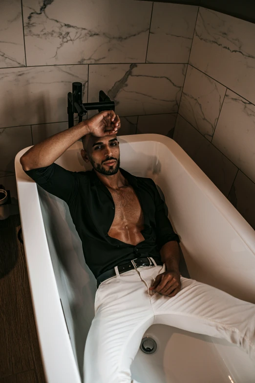 a man in black shirt laying on white tub