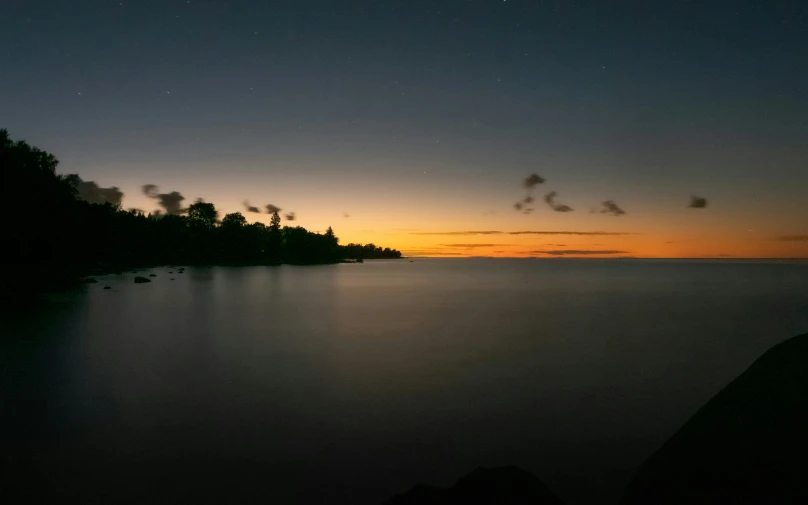 a beautiful sunset behind the shore and an almost empty body of water