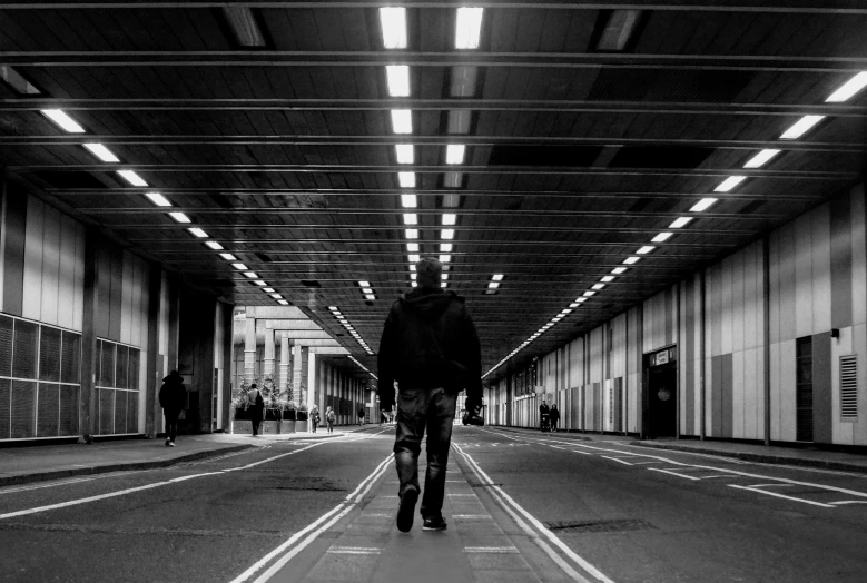 a man walks down a hallway near other buildings