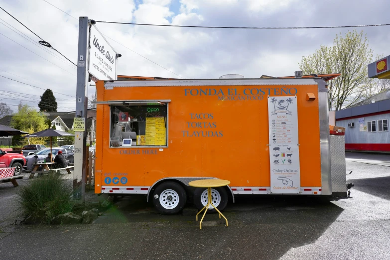 an orange food truck that sells some sort of drink