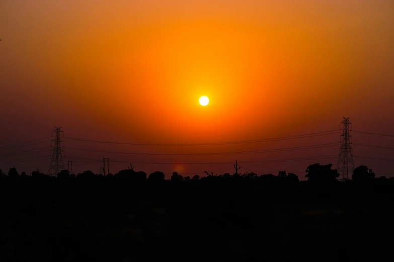 a very bright sun in the sky above some power lines