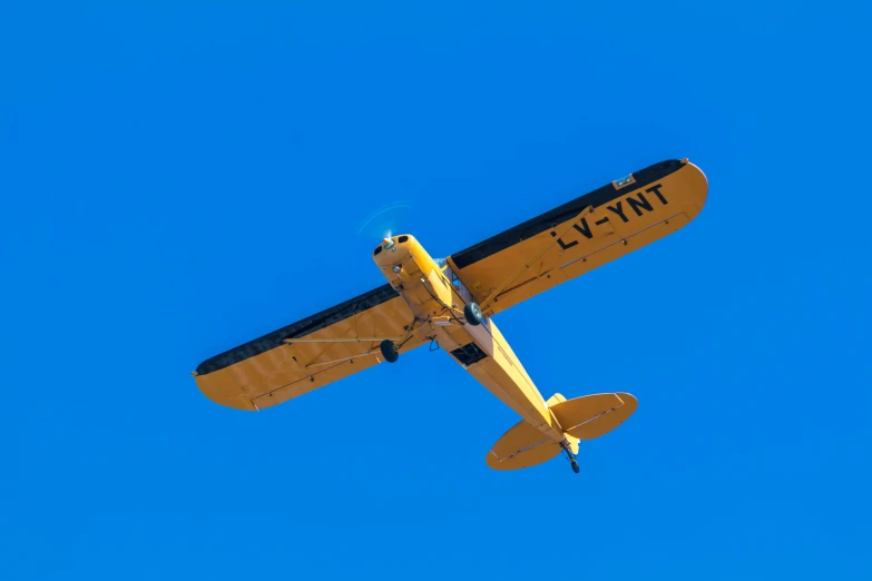 yellow airplane with number two on tail flying against blue sky