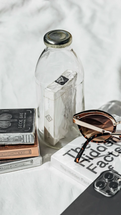 some books, reading glasses and a jar on a table