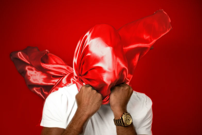 a person covering a red cloth with one hand