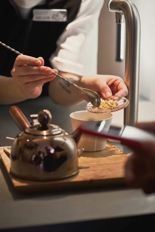 woman preparing a food dish with a saucer and tea kettle