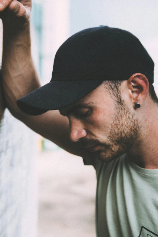 man with black hat leaning against wall