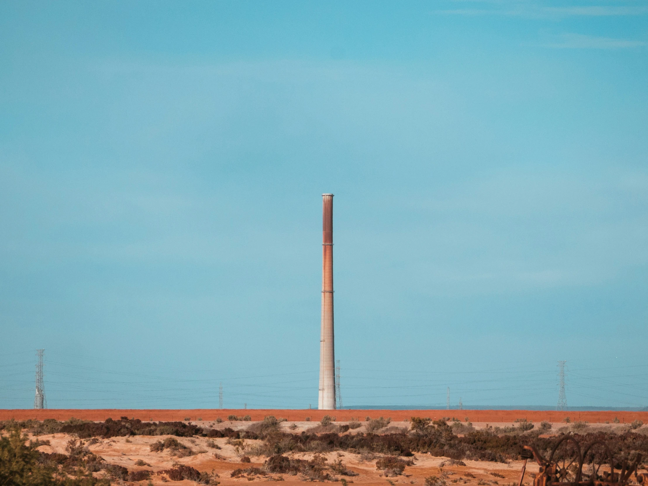 a tall black and white smoke stack in the middle of nowhere