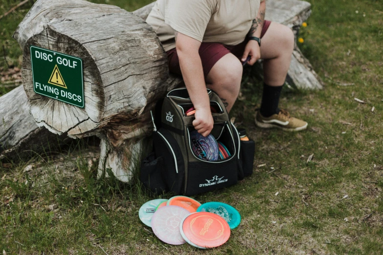 a boy is sitting with a large bag and playing frisbee