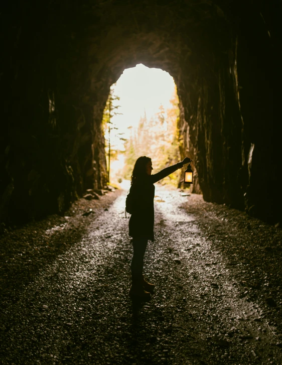 a woman standing in a dark cave holding an umbrella