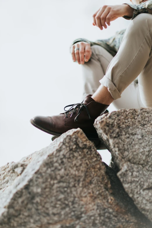 a man in brown shoes sitting on rocks