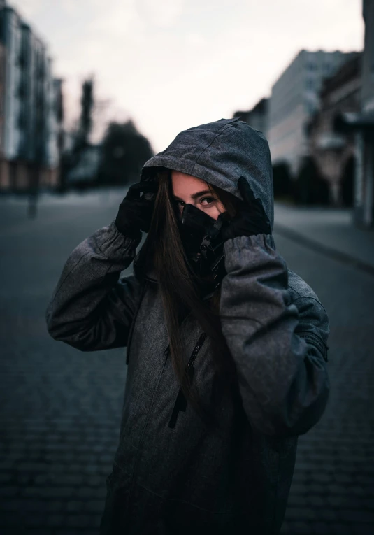 a woman in a black hooded jacket covering her face