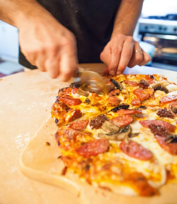 a person  up a small pizza with several toppings