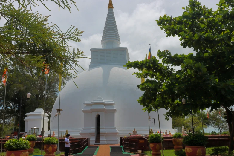 a pagoda sits behind several trees at the end of a walkway