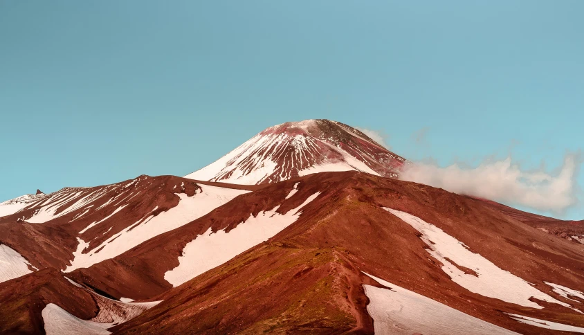 a snowy mountain with clouds in the sky