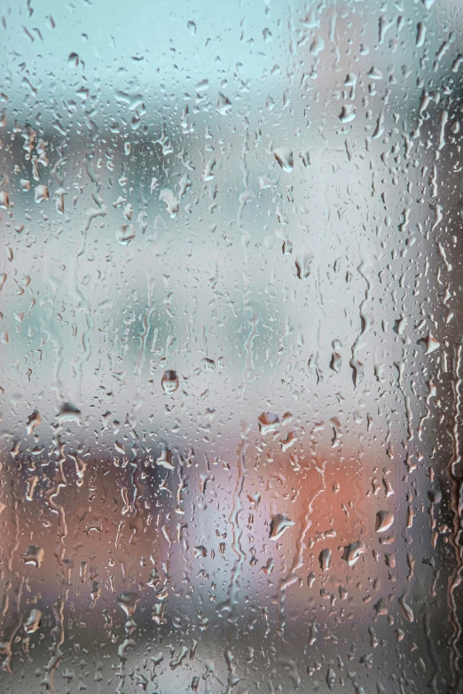 a window has water drops that are looking toward the street