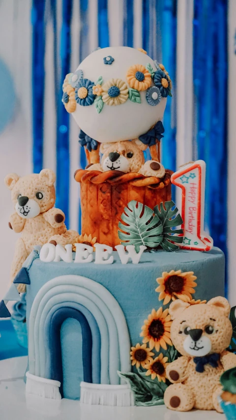 teddy bears on top of a large blue birthday cake
