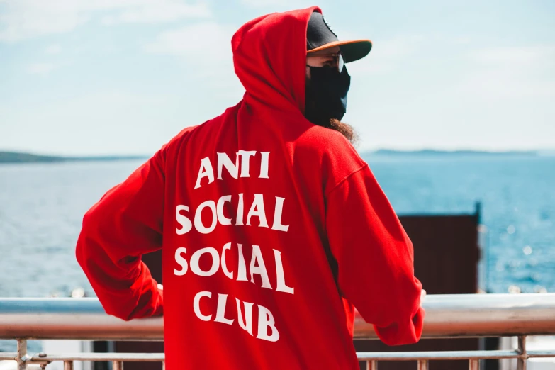 a man wearing a red sweatshirt has a face mask on