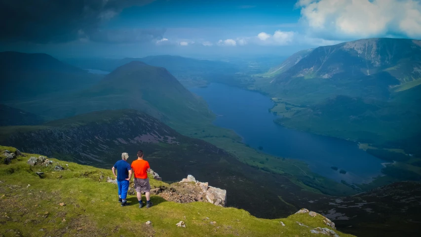 two men are on the top of a mountain looking out at a valley and river