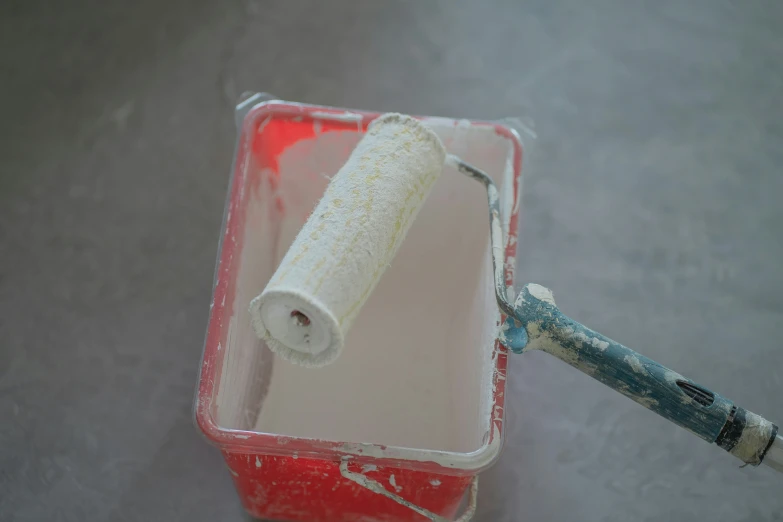 a can of paint with an empty roller in it