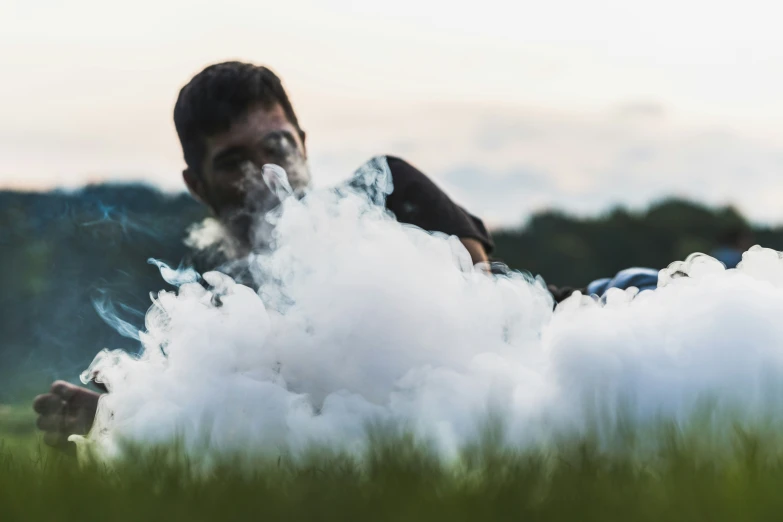 a man standing in a cloud of smoke, holding a cigarette