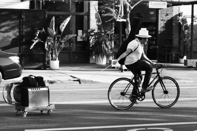 a woman in hat riding a bike down a street