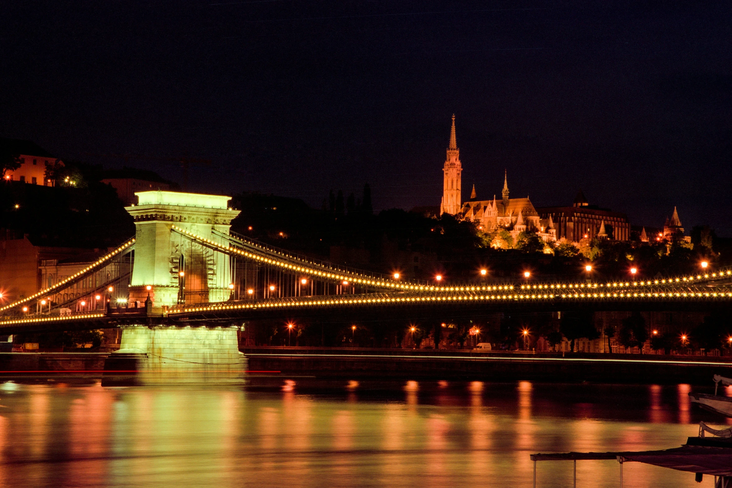 the bridge in front of the building is lit up with bright lights