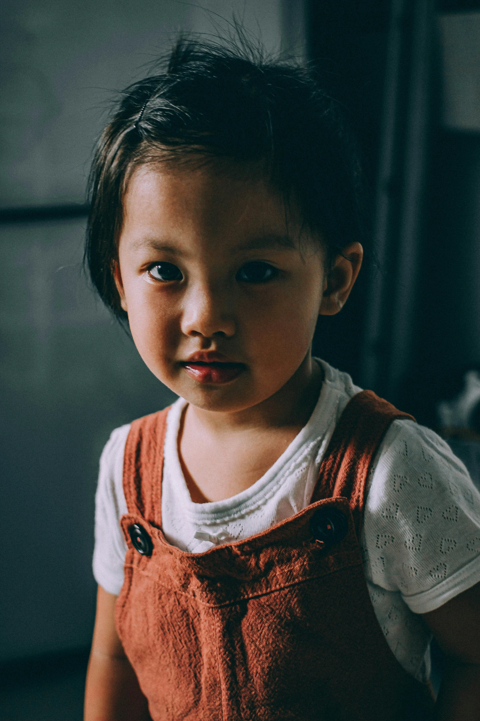 young child in white shirt looking sadly at the camera