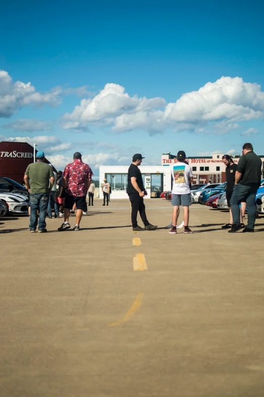 some people are walking around a parking lot with cars