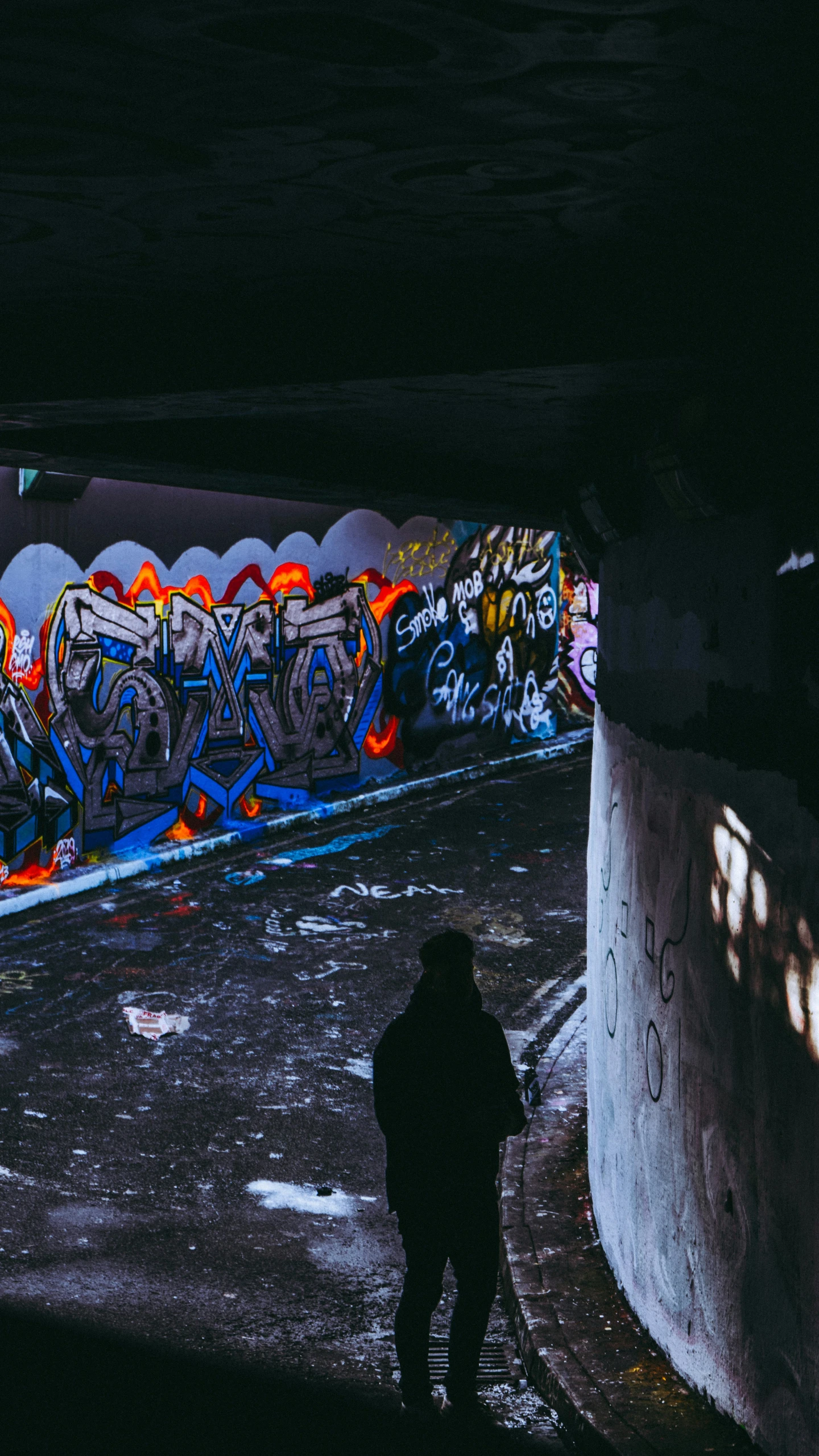 a person standing next to a wall covered in grafitti